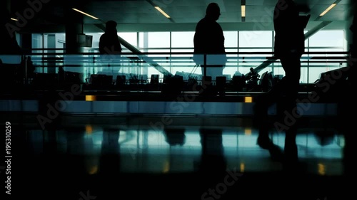 A crowd of unrecognizable silhouettes of passengers in the airport terminal. Go and go by the moving tape. Life in motion - urban scene