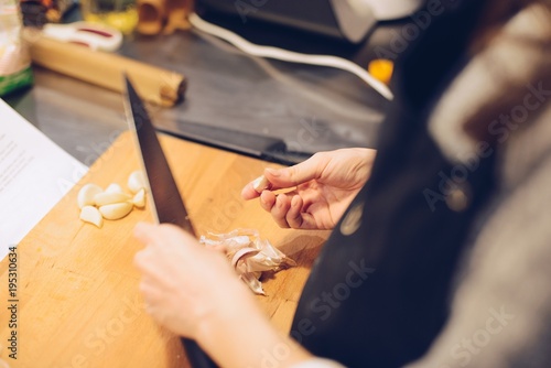 Woman cutting garlic on wooden cutting board