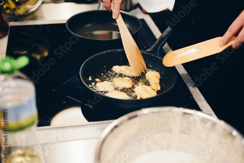 Woman frying breaded fish in hot oil
