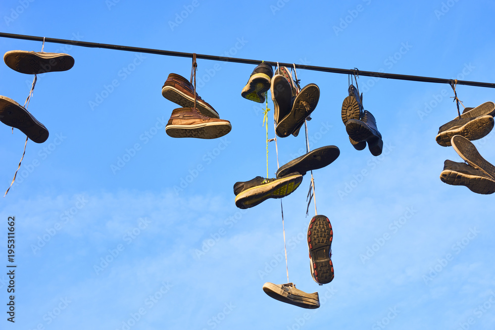 Old Shoes hanging on electrical wire against a sky. Shoe tossing Stock  Photo | Adobe Stock