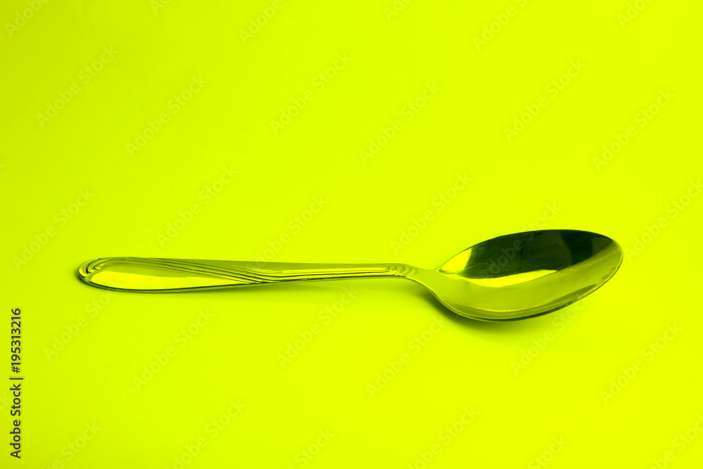 metal spoon close-up isolated on yelow background metal spoon close-up isolated on yelow background