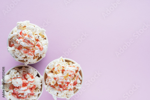 Popcorn in paper cups on a pink background with copy space, top view, flat lay. Cinema concept. Sweet popcorn with strawberry syrup.