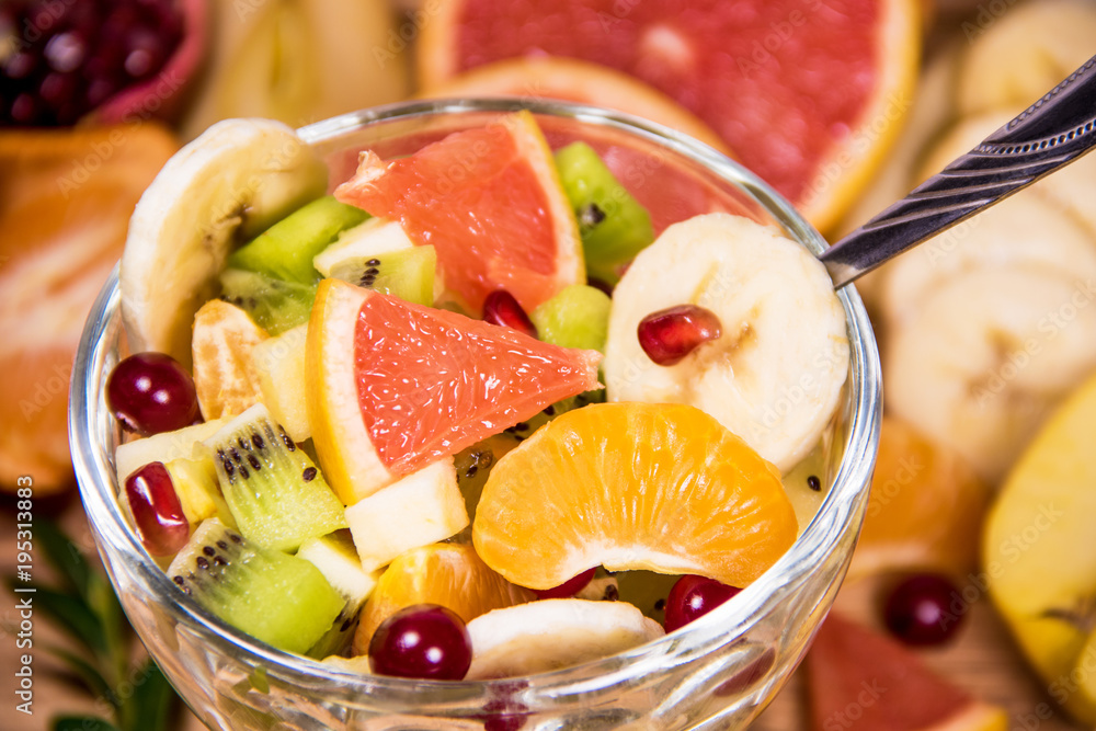 Diet fresh salad in a glass plate on a wooden table with spoon and citrus on background. Detox food ingredient Diet fresh salad in a glass plate on a wooden table with spoon and citrus on background. Detox food ingredient