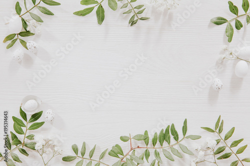 White and green Easter decoration with flowers, leaves and little eggs on white wood