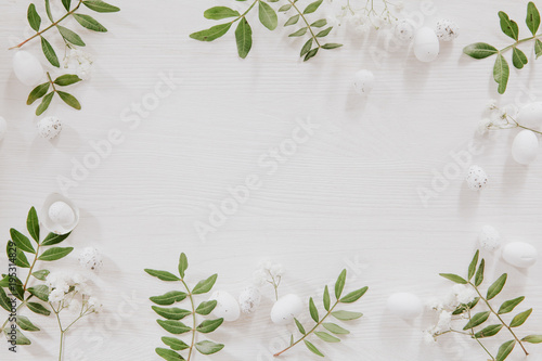 Natural decoration with green leaves, little white eggs and flowers on wooden table