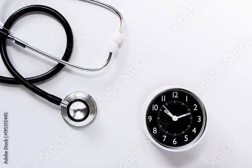 Stethoscope with a clock on white table background. The stethoscope is a medical instrument for listening to the action of someone's heart or breathing.