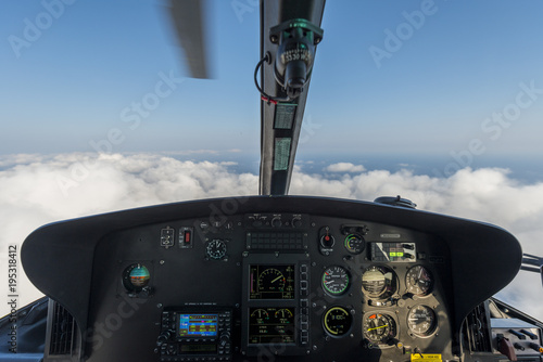 Dashbord of helicopter while flying above the clouds with a moving blade visible