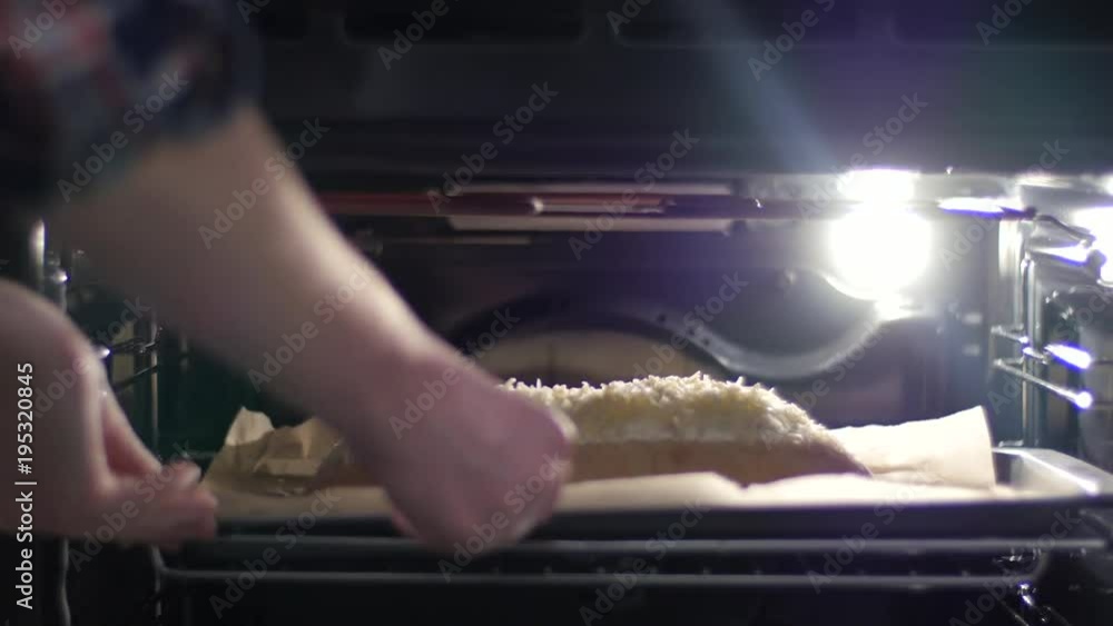 Putting a bread baguette in a baking oven Putting a bread baguette in a baking oven