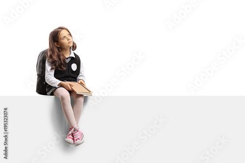 Pensive little schoolgirl sitting on panel