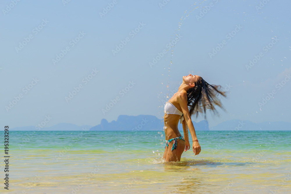 Naklejka premium Beautiful girl splashing water with her hair in the sea.