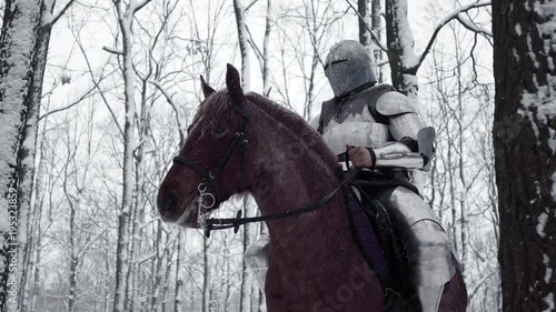 Portrait of frightening armed knight wearing steel protection and helmet, being horseback on battlefield in forest slow motion. Fantasy and reenactment