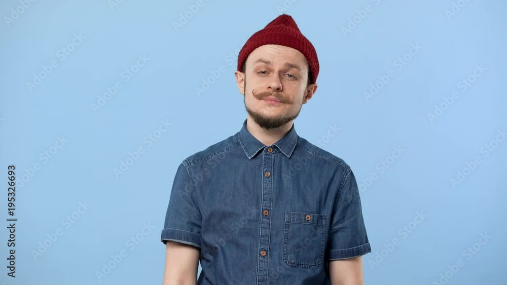 Portrait of caucasian guy 20s with beard and curly mustache yawning and covering mouth with fist due to insomnia, isolated over blue background. Concept of emotions Portrait of caucasian guy 20s with beard and curly mustache yawning and covering mouth with fist due to insomnia, isolated over blue background. Concept of emotions