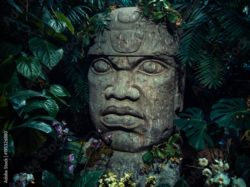Olmec sculpture carved from stone. Big stone head statue in a jungle photo
