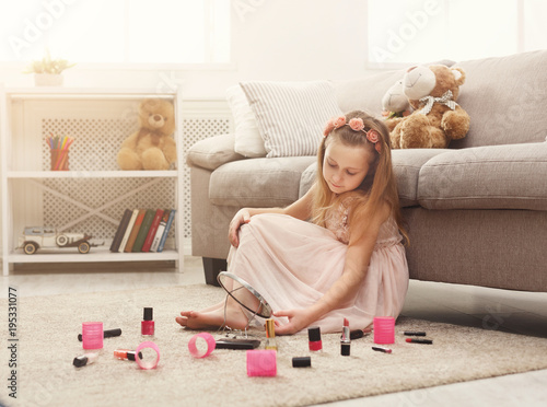 Little girl doing make up with mom`s cosmetics