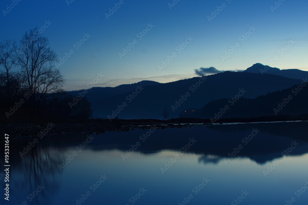 lake and mountain at twilight or blue hour. landscape in Hangu, Ceahlau in background. Romania