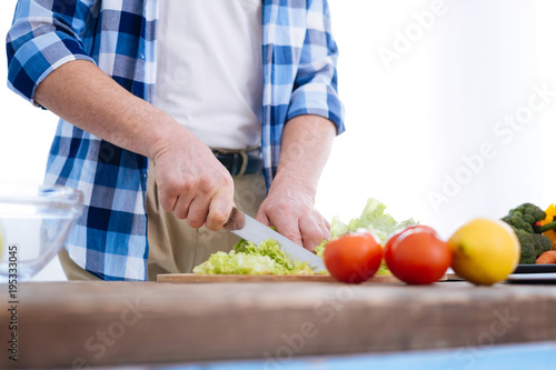 Health benefits. Tender smooth male hands holding knife while chopping salad and cooking dinner