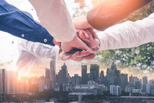 the double exposure image of the many businessmen take a hands together during sunrise overlay with cityscape image. The concept of agreement, business, cooperation, partnership and successful. photo