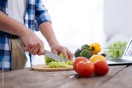 Vitamins in food. Close up of male attractive hands crumbling lettuce for making dinner and consuming vitamins