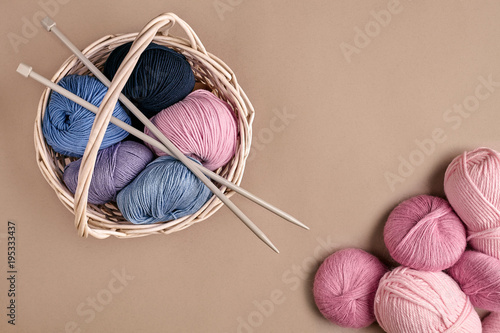 Different colored yarn in basket with knitting needles. Top view photo