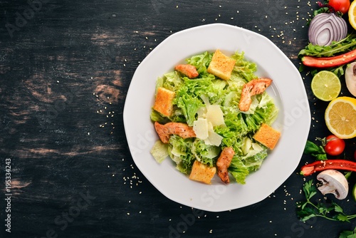 Caesar salad with chicken and fresh vegetables. On a wooden background. Top view. Copy space.