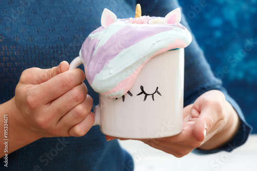 Mug in woman hands with colorful cream