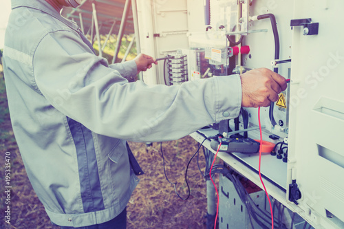 solar power plant to innovation of green energy; engineer or electrician working on checking and maintenance equipment at solar power plant.