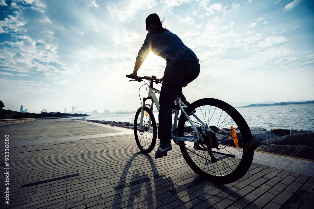 Fototapeta premium cyclist riding bike in the sunrise coast path
