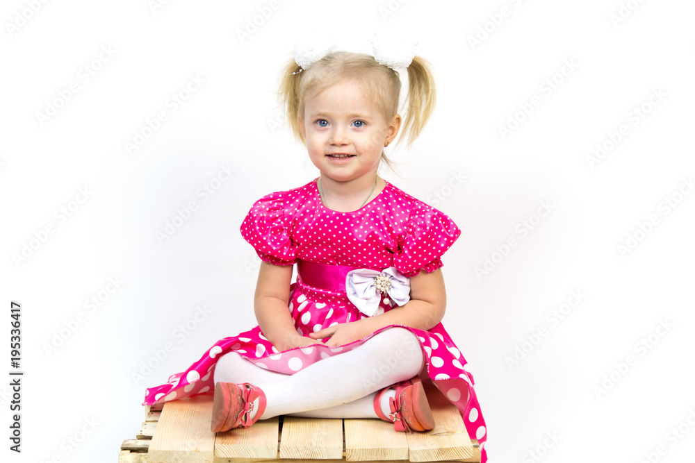 Little girl 3 years old in a red dress with bows in her hair. Beautiful girl in a beautiful fluffy dress posing against a white wall. Little girl 3 years old in a red dress with bows in her hair. Beautiful girl in a beautiful fluffy dress posing against a white wall.