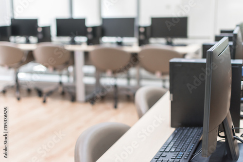 Computer lab blur background with pc desktop computer machine in blurry school class or office desk workspace