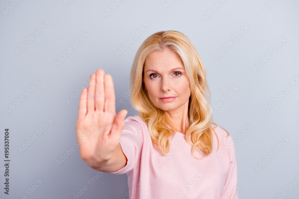 Close up portrait of serious focused concentrated emotion expressing beautiful grandmother granny grandma stretching arm making sign stop with hand modern stylish hairdo isolated on gray background Close up portrait of serious focused concentrated emotion expressing beautiful grandmother granny grandma stretching arm making sign stop with hand modern stylish hairdo isolated on gray background