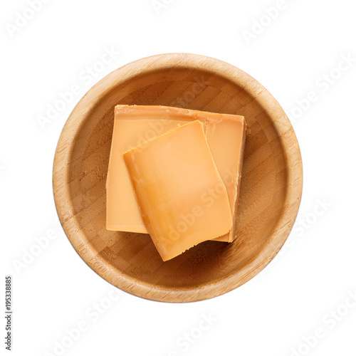 Norwegian brunost in wooden bowl Isolated on white. Traditional Scandinavian brown cheese. Top view. photo