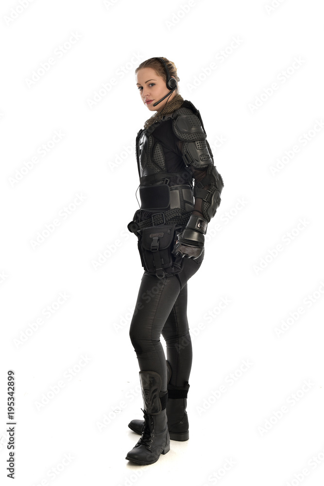 full length portrait of female soldier wearing black tactical armour, standing in side profile, isolated on white studio background. full length portrait of female soldier wearing black tactical armour, standing in side profile, isolated on white studio background.