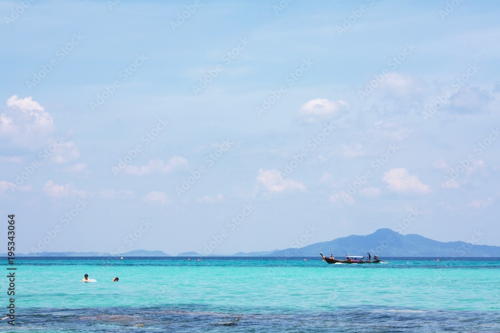 Seascape, boat sailing on the azure sea, two swimmers in masks in the water