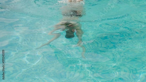 girl swims in the outdoor pool at the hotel in a black swimsuit