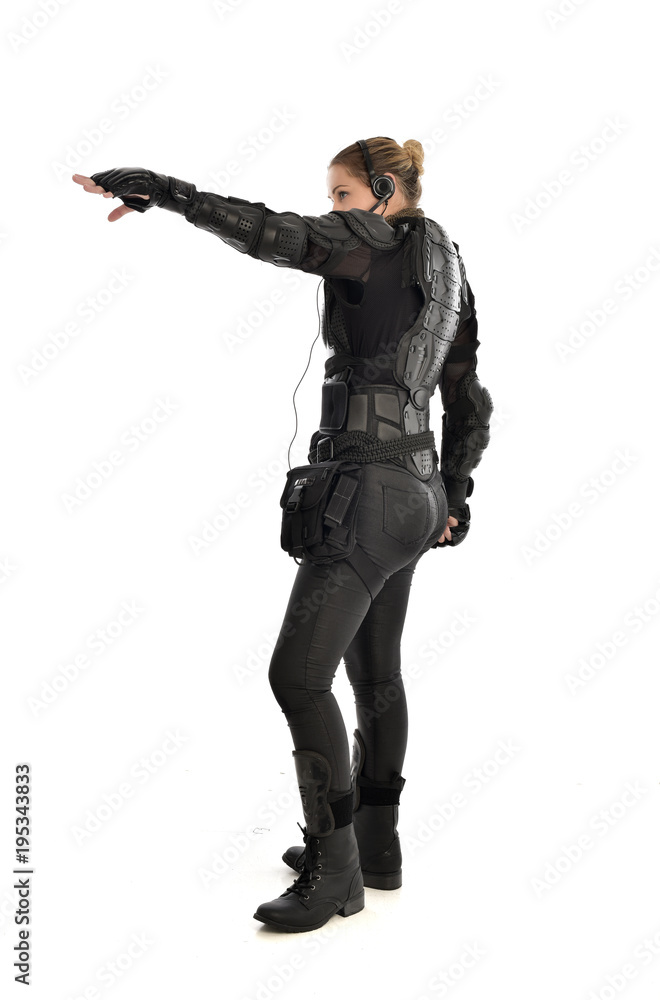 full length portrait of female soldier wearing black tactical armour, standing in side profile, isolated on white studio background. full length portrait of female soldier wearing black tactical armour, standing in side profile, isolated on white studio background.