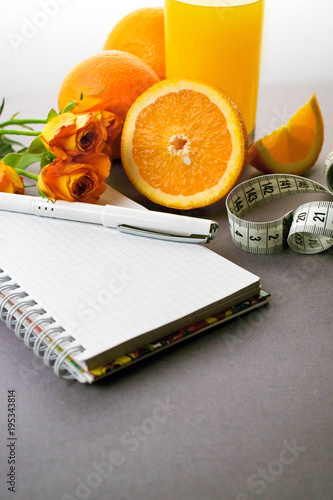 Still life on a gray background. Composition of orange, inch, notebook. A place for a label