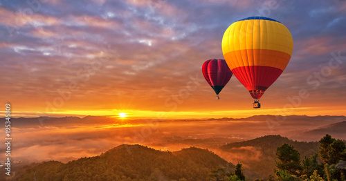 Colorful hot-air balloons flying over misty morning sunrise at Chiang Mai, Thailand..