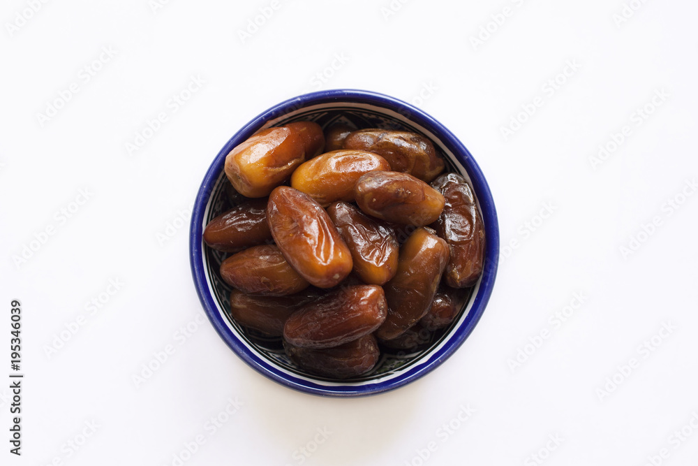 dates in the oriental style bowl. bowl with oriental pattern. oriental sweets. a few dates near the pial. date fruit. dried fruit. dates in the oriental style bowl. bowl with oriental pattern. oriental sweets. a few dates near the pial. date fruit. dried fruit.