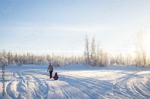 Mother and child sledding in winter 
