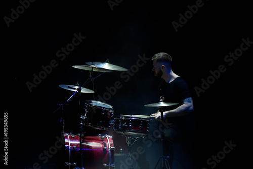 music, people, musical instruments and entertainment concept - male musician with drumsticks playing drums on the stage. © nagaets
