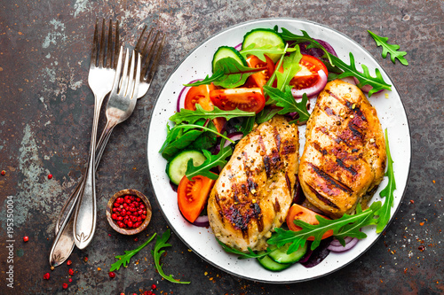 Grilled chicken breast. Fried chicken fillet and fresh vegetable salad of tomatoes, cucumbers and arugula leaves. Chicken meat with salad. Healthy food