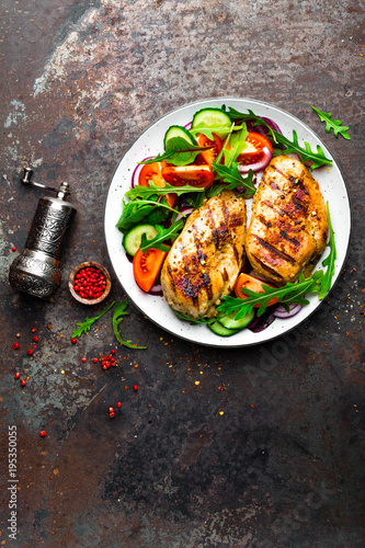 Grilled chicken breast. Fried chicken fillet and fresh vegetable salad of tomatoes, cucumbers and arugula leaves. Chicken meat with salad. Healthy food