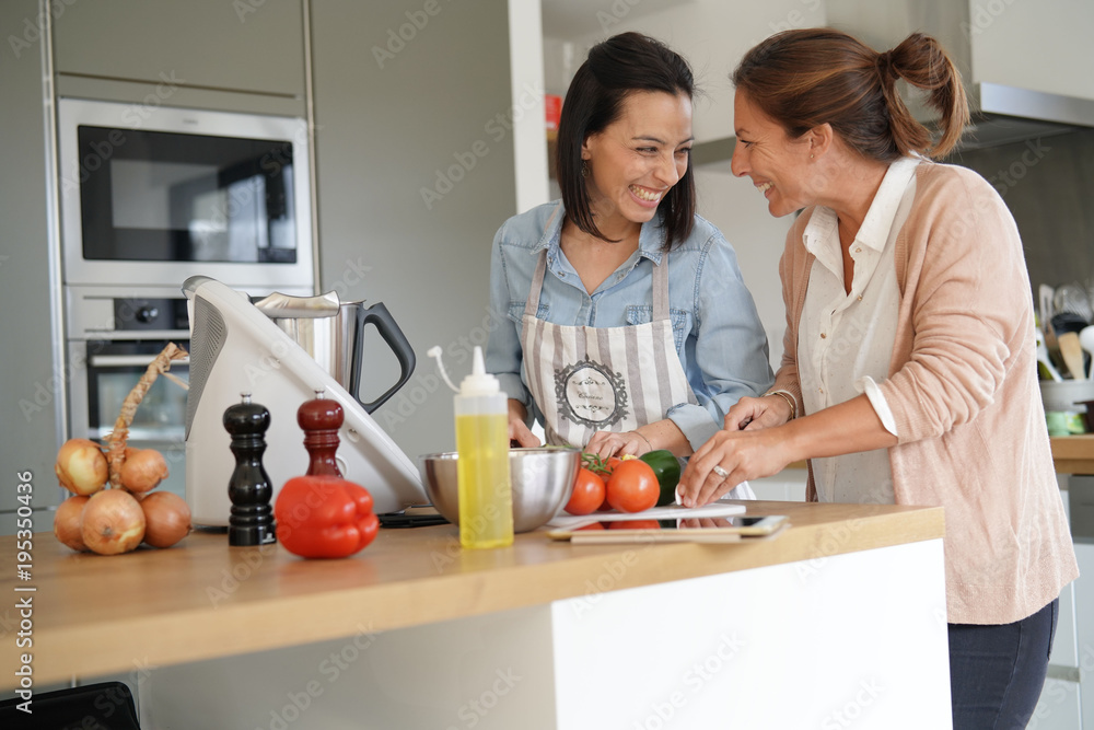 Friends cooking together with kitchen robot and tablet Friends cooking together with kitchen robot and tablet