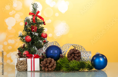 Little beautifully decorated Christmas tree, gifts, cones, toy-balloons, on yellow background