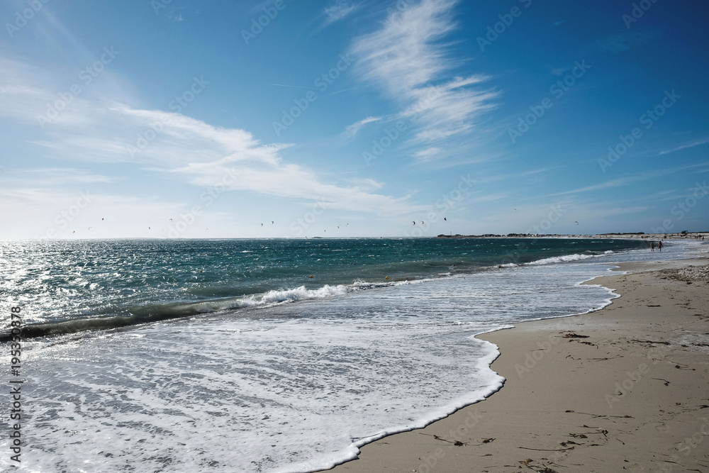 soft wave on the beach with kitesurfer on the horizon soft wave on the beach with kitesurfer on the horizon