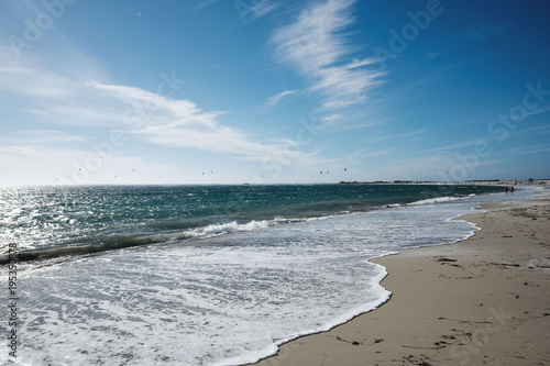 soft wave on the beach with kitesurfer on the horizon 