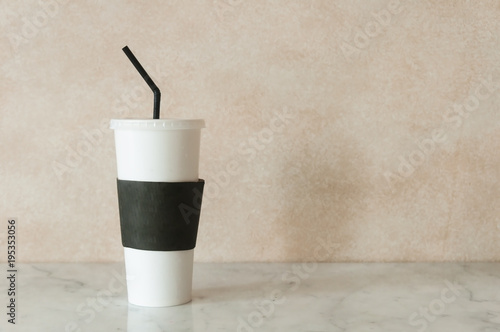 Paper ice coffee mug on marble table with texture background.