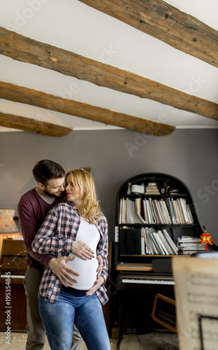 Young man and pregnant woman hugging in the room