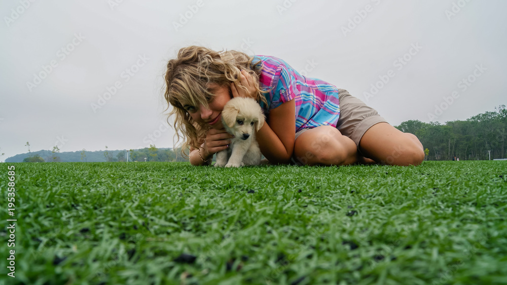 Fototapeta premium Pretty young girl lying on the grass with her 3 month old labrador puppy