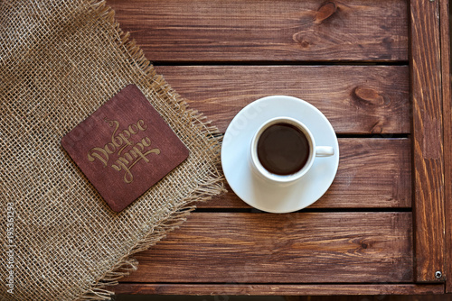 Чашка кофе с салфеткой из мешковины и подставкой под горячие напитки на деревянном коричневом фоне
